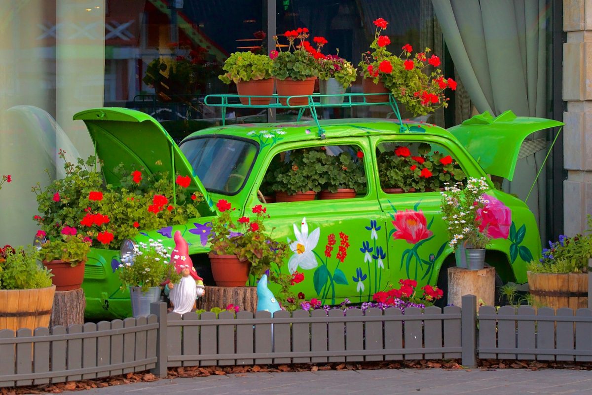 a green car is decorated with flowers and potted plants