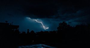 Powerful lightning bolt illuminates an urban skyline at night, showcasing nature's raw power.