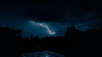 Powerful lightning bolt illuminates an urban skyline at night, showcasing nature's raw power.