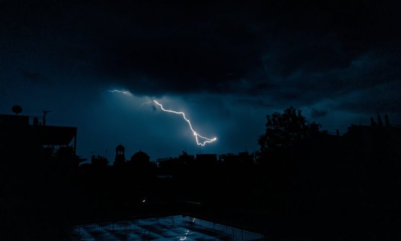 Powerful lightning bolt illuminates an urban skyline at night, showcasing nature's raw power.