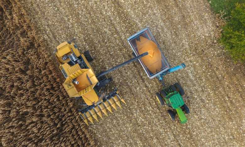 an aerial view of a tractor and a combine in a field