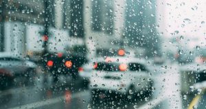 Blurred city traffic seen through a window with raindrops, a perfect rainy day scene.