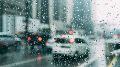 Blurred city traffic seen through a window with raindrops, a perfect rainy day scene.