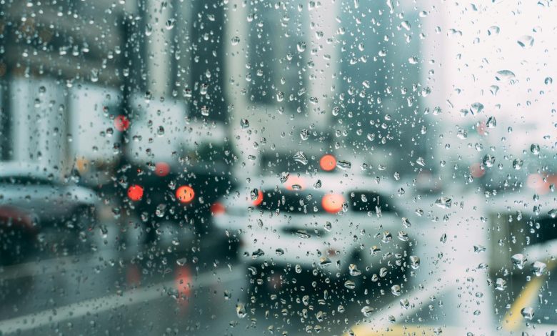 Blurred city traffic seen through a window with raindrops, a perfect rainy day scene.