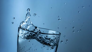 A dynamic splash of water in a clear glass against a blue background.
