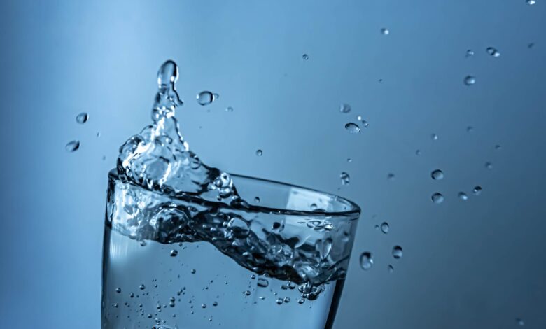A dynamic splash of water in a clear glass against a blue background.