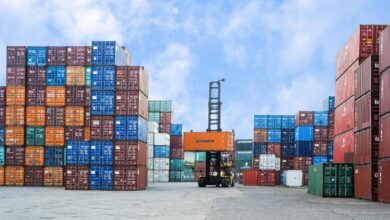 Colorful shipping containers and forklift in a busy Jakarta port under blue skies.