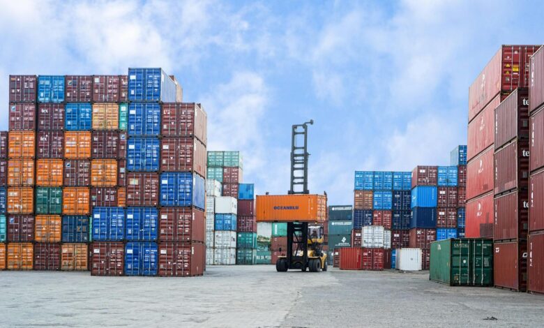 Colorful shipping containers and forklift in a busy Jakarta port under blue skies.