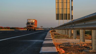 A solitary truck travels down a deserted highway at sunset, with clear blue skies overhead.