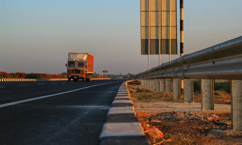A solitary truck travels down a deserted highway at sunset, with clear blue skies overhead.