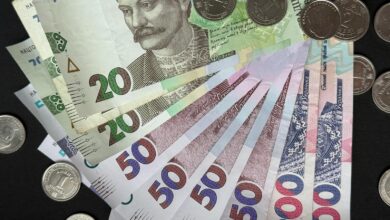 Close-up of assorted Ukrainian banknotes and coins on a dark background.