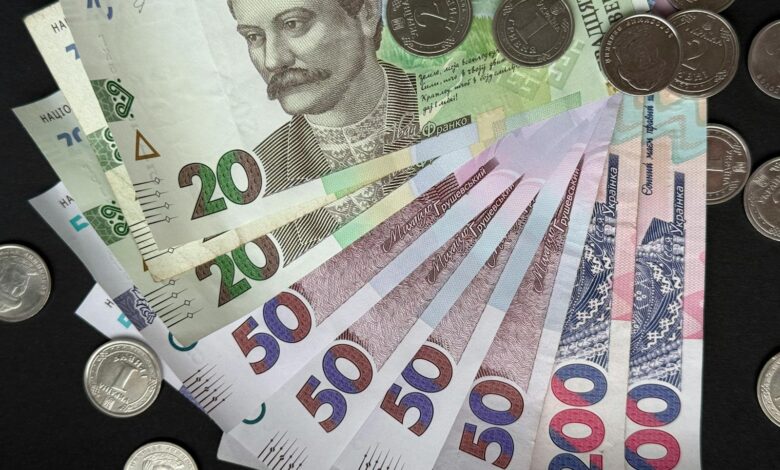 Close-up of assorted Ukrainian banknotes and coins on a dark background.