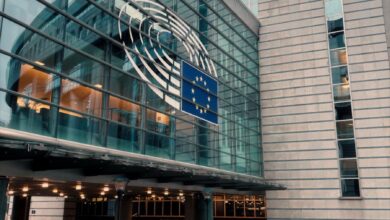 Exterior of the European Parliament in Brussels, showcasing modern architecture and the EU flag.