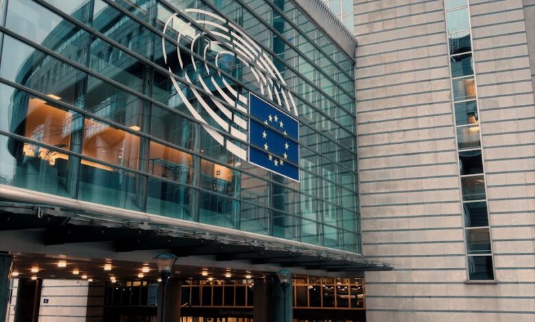 Exterior of the European Parliament in Brussels, showcasing modern architecture and the EU flag.
