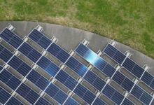 Top-down view of solar panels arranged on a green field, highlighting renewable energy.