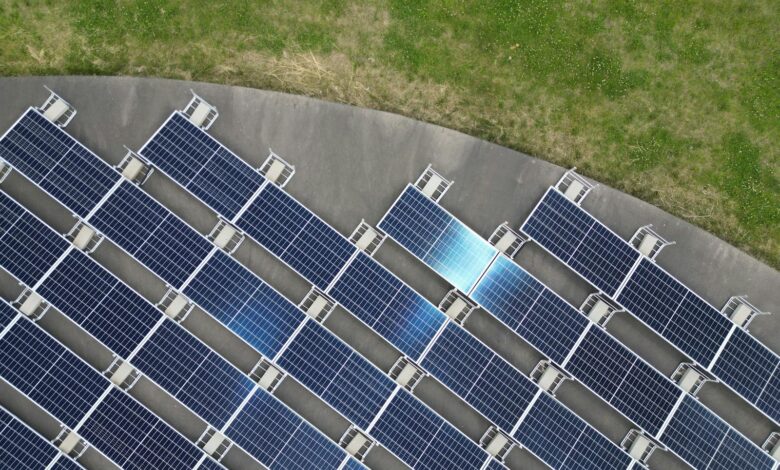 Top-down view of solar panels arranged on a green field, highlighting renewable energy.