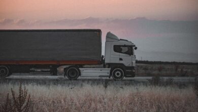 A cargo truck travels on a highway at sunset, surrounded by an open landscape, symbolizing logistics and transportation.