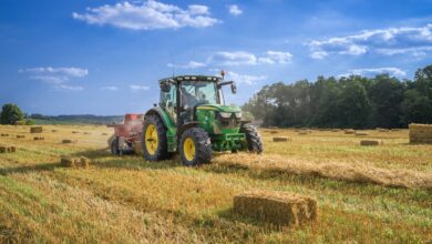green tractor on brown grass field under blue sky during daytime