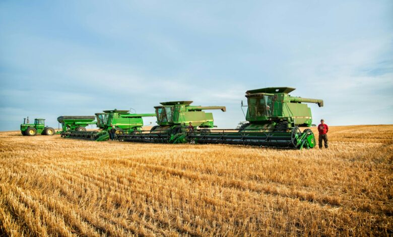 a man standing in a field next to a row of green farm equipment