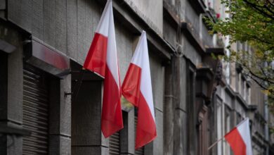Polish flags hanging on a historic urban building, symbolizing national pride.