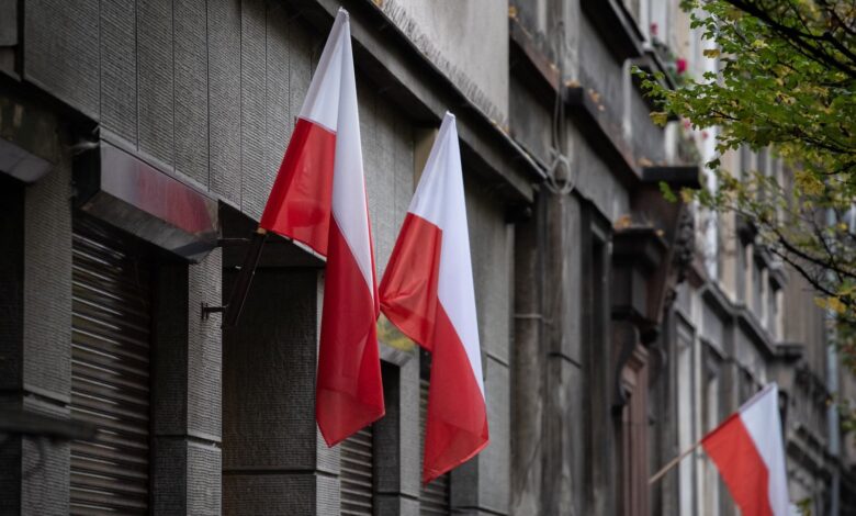 Polish flags hanging on a historic urban building, symbolizing national pride.