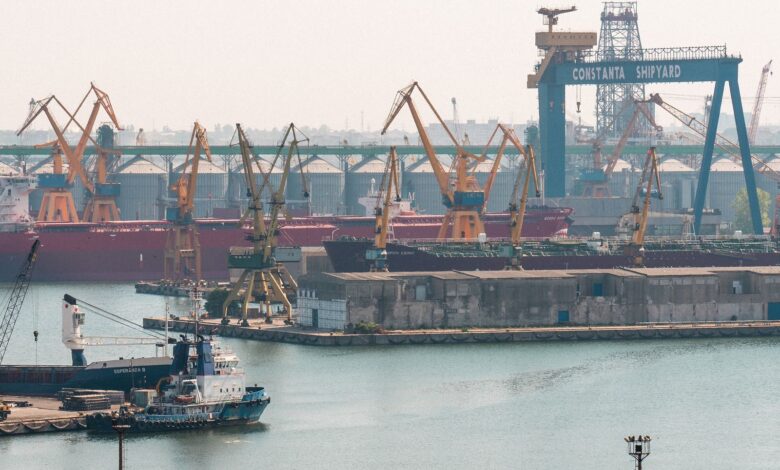 A busy scene at Constanta Shipyard, Romania, featuring cranes and cargo ships in the harbor.