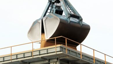 Clamshell grab unloading bulk cargo at an industrial port terminal.