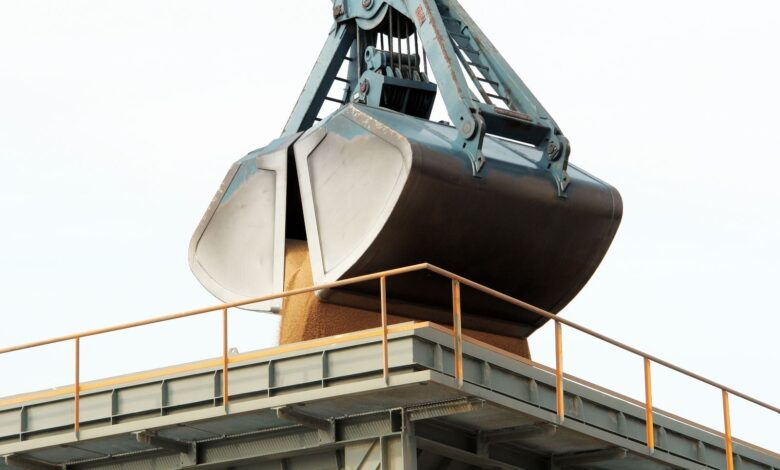 Clamshell grab unloading bulk cargo at an industrial port terminal.