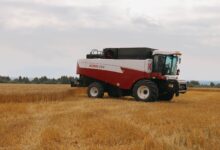A combine harvester at work in a golden wheat field under a cloudy sky. Ideal for agriculture themes.