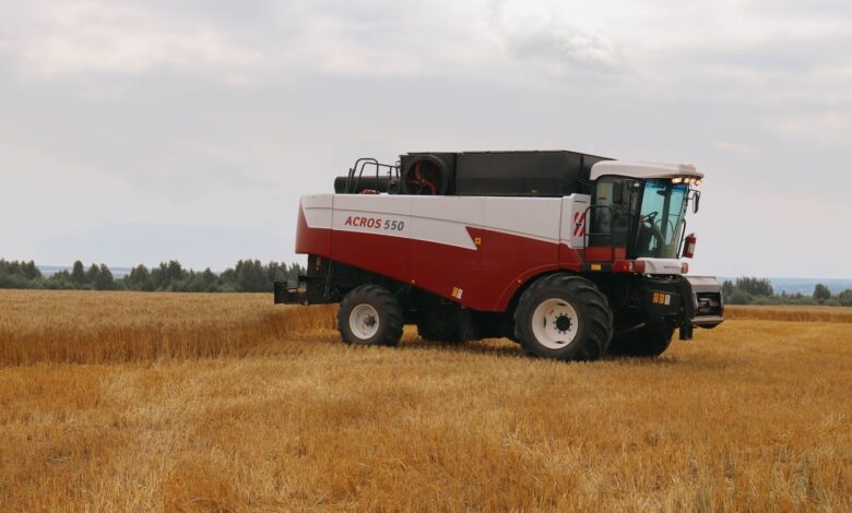 A combine harvester at work in a golden wheat field under a cloudy sky. Ideal for agriculture themes.