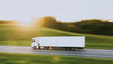 a white semi truck driving down a rural road