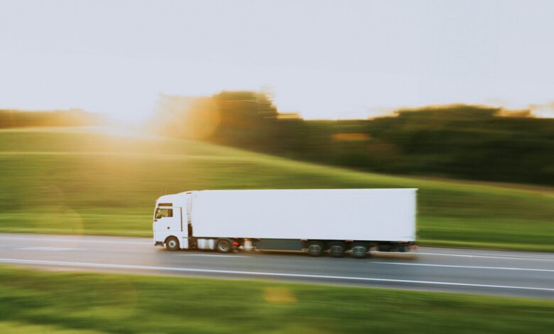 a white semi truck driving down a rural road