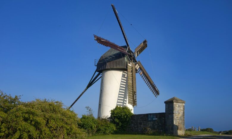 A windmill sitting on top of a lush green field