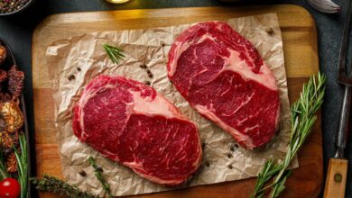 two steaks on a cutting board with herbs and spices