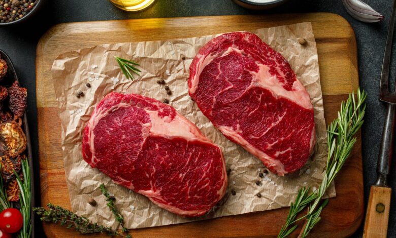 two steaks on a cutting board with herbs and spices