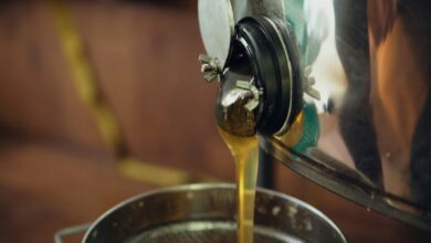 Golden honey streams into a metal container