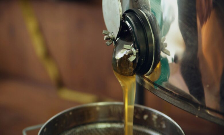 Golden honey streams into a metal container